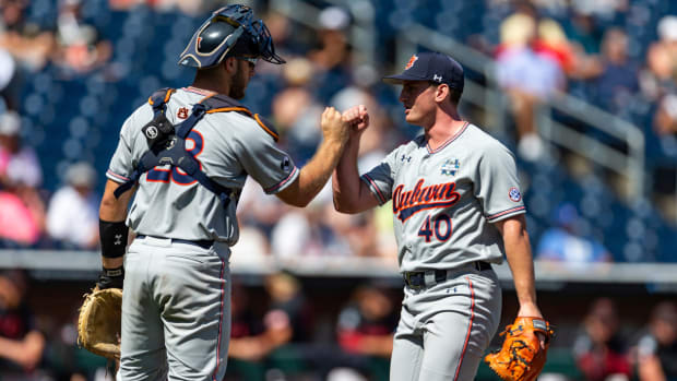 Auburn pitcher Blake Burkhalter (40) and catcher Nate LaRue (28) fist bump after the seventh inning of a College World Series Game against Stanford.