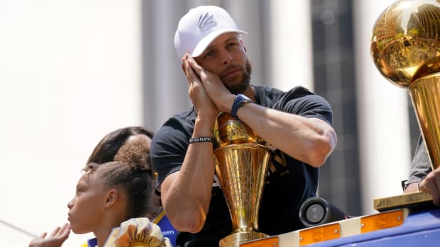 Warriors guard Stephen Curry poses with the NBA Finals Most Valuable Player Award trophy during the team’s victory parade.