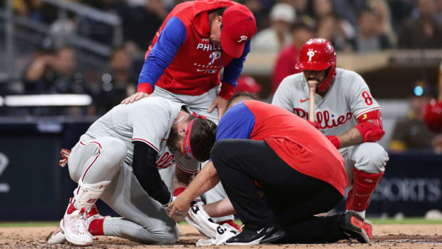 Philadelphia Phillies’ Bryce Harper, left, receives attention after being hit by a pitch while interim manager Rob Thomson, background left, and Nick Castellanos, background right, look on during the fourth inning of the team’s baseball game against the San Diego Padres, Saturday, June 25, 2022, in San Diego. (AP Photo/Derrick Tuskan)