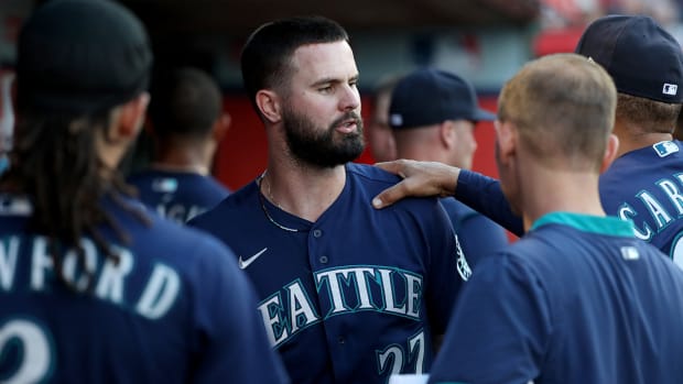 Mariners left fielder Jesse Winker (27) is congratulated by teammates after scoring a run against the Angels.