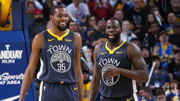 Warriors forward Kevin Durant (35) smiles with forward Draymond Green (23) after a play.