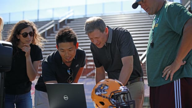 Kei Kawata works with his team on the football field sidelines.