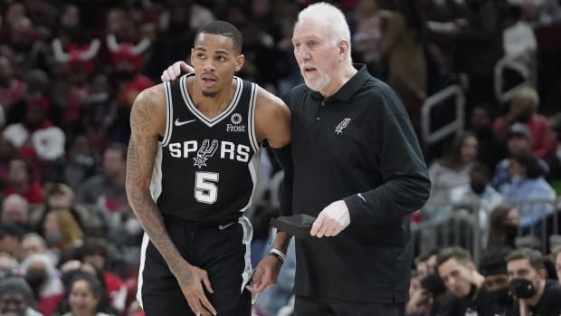 Spurs guard Dejounte Murray and head coach Gregg Popovich speak during a stoppage in play.