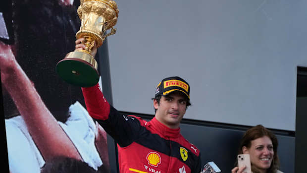 Ferrari driver Carlos Sainz of Spain holds his trophy up as celebrates on the podium after winning the British Formula One Grand Prix at the Silverstone circuit, in Silverstone, England, Sunday, July 3, 2022. (AP Photo/Frank Augstein)