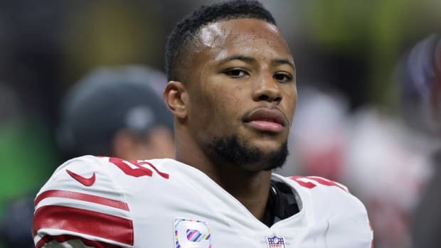 Giants running back Saquon Barkley on the sidelines without a helmet during a game.