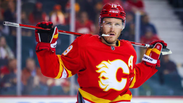 Flames forward Matthew Tkachuk holds his stick on his shoudlers during a stoppage in play.