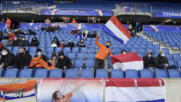 A French fan waves a flag in the stands of a women's friendly soccer match.