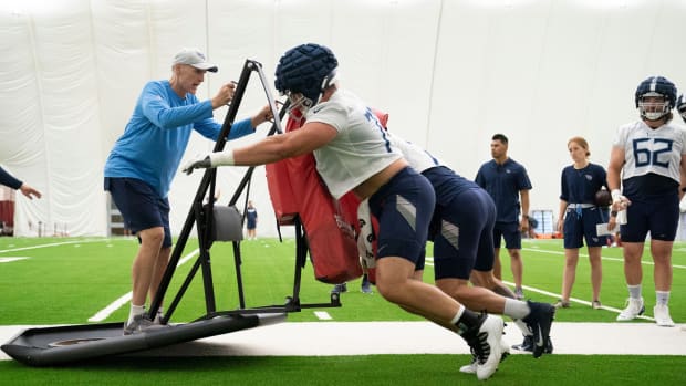 Tennessee Titans offensive line assistant coach Mike Sullivan takes a ride on a tackling sled as offensive tackles Dillon Radunz (75) and Taylor Lewan (77) push it across the field during a training camp practice at Saint Thomas Sports Park Friday, July 29, 2022, in Nashville, Tenn.