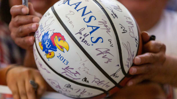 A fan asks Kansas men's basketball team players to sign a Jayhawks-branded ball inside the terminal at Topeka Regional Airport at Forbes Field on Tuesday, April 2, 2022. Kansas Jayhawks Return Home Champions 15