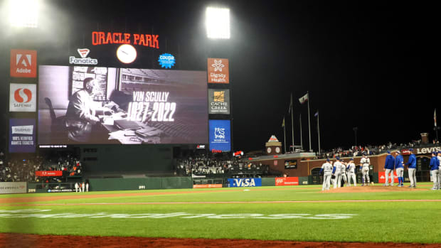 The video board displays a tribute to Vin Scully who passed away earlier in the day as Los Angeles Dodgers players high five after a win against the San Francisco Giants at Oracle Park.