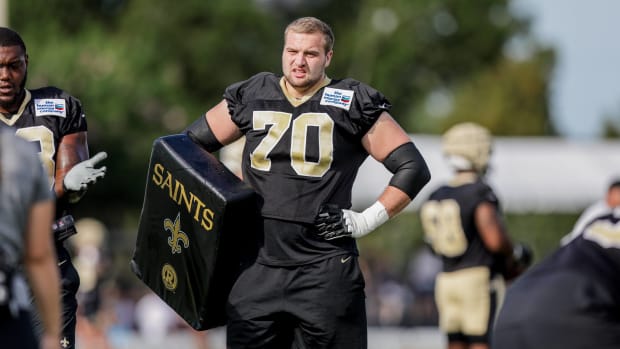Saints offensive lineman Trevor Penning stands on the sidelines of practice with a blocking pad.