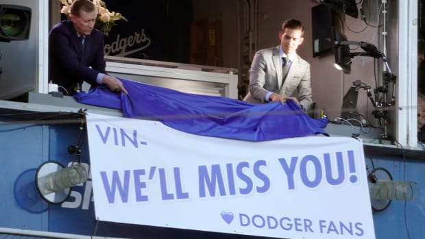 Broadcasters Orel Hershiser, left, and Joe Davis unveil a banner during a ceremony to honor the memory of Los Angeles Dodgers announcer Vin Scully.