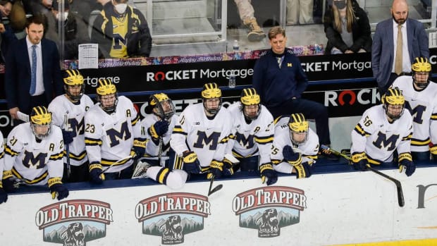 The Michigan hockey team's bench watches a play during a game.