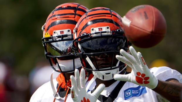 Cincinnati Bengals wide receiver Tee Higgins (85) catches passes from Jugs football passing machine as wide receiver Ja'Marr Chase (1), background, assists at the conclusion of Cincinnati Bengals training camp practice, Friday, July 29, 2022, at the practice fields next to Paul Brown Stadium in Cincinnati. Cincinnati Bengals Training Camp July 29 0033