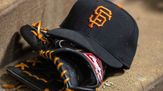 An SF Giants hat resting on a glove in the dugout.