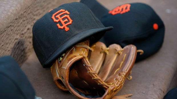 A pair of SF Giants hat resting on a glove on the dugout steps.