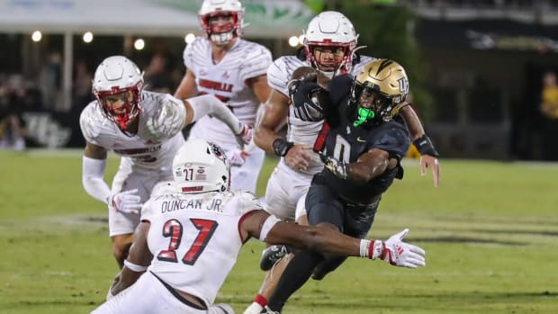 Sep 9, 2022; Orlando, Florida, USA; UCF Knights running back Johnny Richardson (0) runs the ball as Louisville Cardinals defensive back Kenderick Duncan (27) moves in during the second quarter at FBC Mortgage Stadium. Mandatory Credit: Mike Watters-USA TODAY Sports