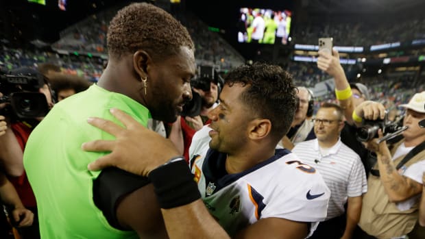Seahawks wide receiver DK Metcalf, left, talks with Broncos quarterback Russell Wilson, center, after a Monday night football game between the two teams.