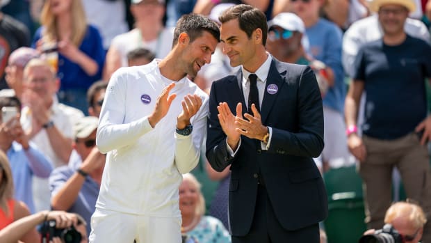 Novak Djokovic talks to Roger Federer during a ceremony at the 2022 Wimbledon championships.