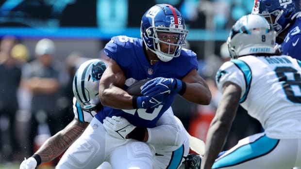 Sep 18, 2022; East Rutherford, New Jersey, USA; New York Giants running back Saquon Barkley (26) runs with the ball against Carolina Panthers linebacker Frankie Luvu (49) and cornerback Jaycee Horn (8) during the first quarter at MetLife Stadium.