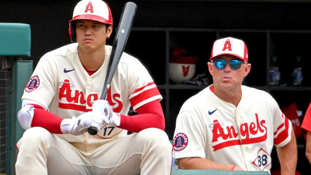 Angles two-way player Shohei Ohtani sits next to manager Phil Nevin in the on deck circle as both watch the game.