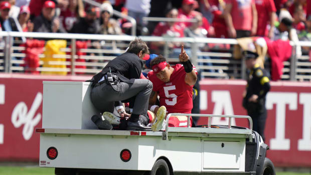 Trey Lance gestures to the crowd as he's carted off after an ankle injury