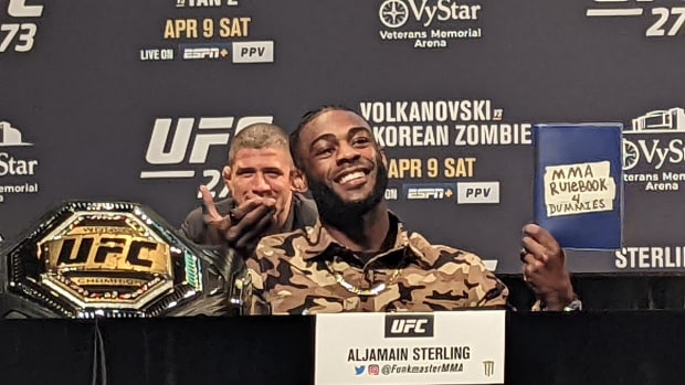 Bantamweight champion Aljamain Sterling holds an "MMA Rulebook 4 Dummies" to taunt interim champion Petr Yan (not pictured) during a press conference at UFC 273.