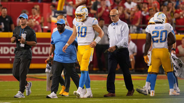 Chargers quarterback Justin Herbert walks off the field with team trainers after injuring his ribs vs. Kansas City.