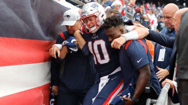 New England Patriots quarterback Mac Jones (10) is helped off the field after suffering a leg injury with less than two minutes to play in the second half of an NFL football game against the Baltimore Ravens.