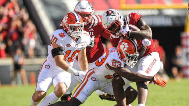 Clemson linebacker Baylon Spector (10) and cornerback Andrew Booth Jr. (23) tackle N.C. State running back Zonovan Knight (7)