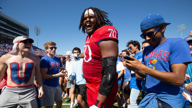 Kansas redshirt sophomore offensive linebacker Kobe Baynes (70) celebrates with fans as they run on to the field Saturday after defeating Duke 35-27 at David Booth Kansas Memorial Stadium.