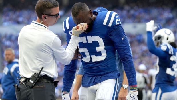 Indianapolis Colts assistant athletic trainer Kyle Davis tends to linebacker Shaquille Leonard (53) after a play against the Tennessee Titans during the first half at Lucas Oil Stadium.