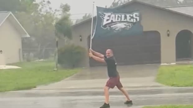 Gabe Ferraro holds up an Eagles flag in the rain and wind as Hurricane Ian approaches
