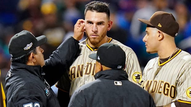 Umpire Alfonso Márquez checks for substances behind the ears of Padres pitcher Joe Musgrove.