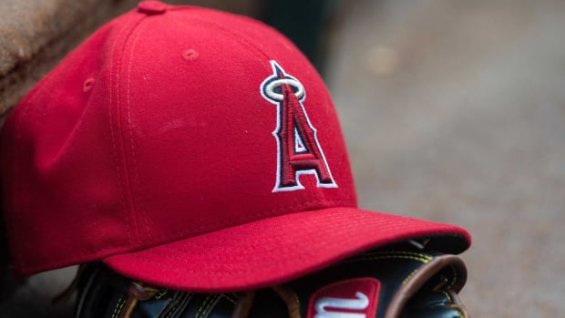 A Los Angeles Angels hat sitting on a baseball glove in a dugout.