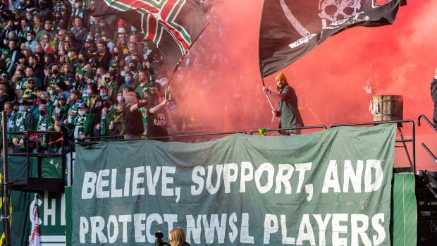 Portland Thorns fans hold up a banner that says, “Believe, support, and protect NWSL players.”