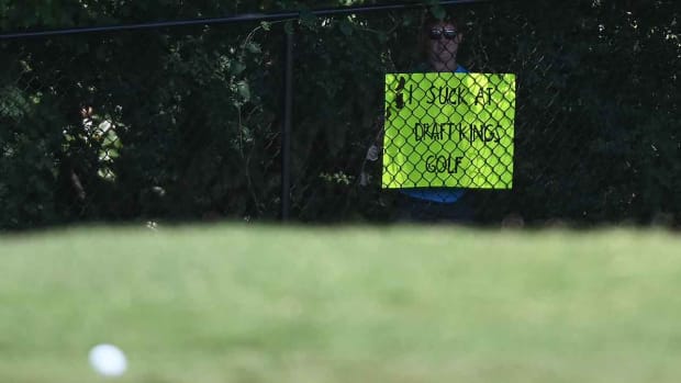 A fan holds up a sign reading "I Suck at DraftKings Golf" during the final round of 2020 Tour Championship.