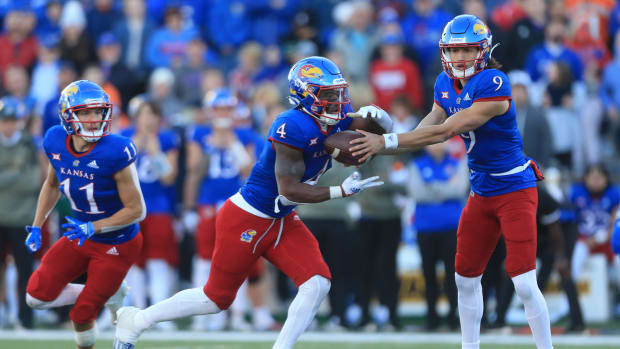 Kansas redshirt senior quarterback Jason Bean (9) hands the ball to sophomore running back Devin Neal (4) with junior wide receiver Luke Grimm (11) running in the back during the fourth quarter of Saturday's game at David Booth Kansas Memorial Stadium.