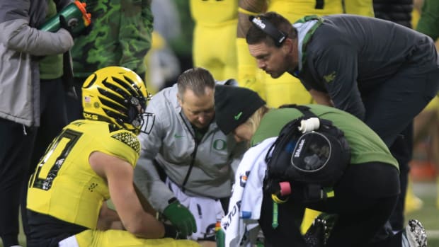 Oregon quarterback Bo Nix, left, sits in the turf after being injured on a fourth quarter play against Washington, Saturday, Nov. 12, 2022, at Autzen Stadium in Eugene, Ore.