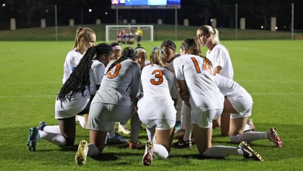 The Virginia women's soccer team kneels in a huddle before a match against Fairleigh Dickinson.