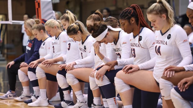 The Virginia volleyball team kneels during a moment of silence before the match against Wake Forest at Memorial Gymnasium.