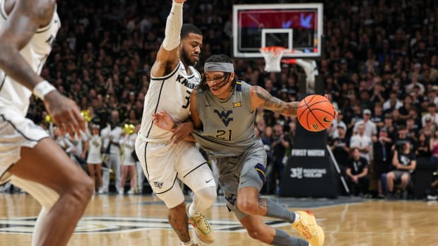 Jan 23, 2024; Orlando, Florida, USA; West Virginia Mountaineers guard RaeQuan Battle (21) drives to the basket around UCF Knights guard Darius Johnson (3) during the first half at Addition Financial Arena. Mandatory Credit: Mike Watters-USA TODAY Sports