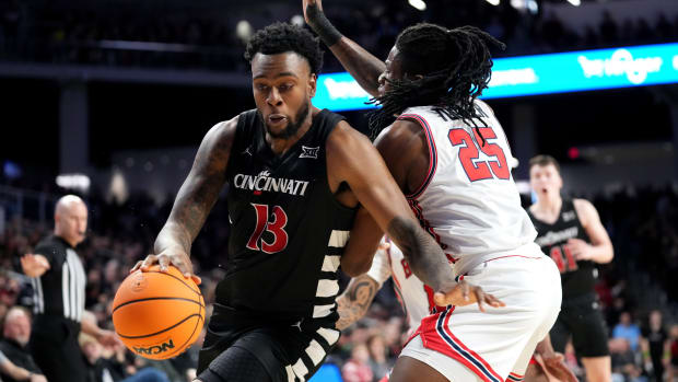 Cincinnati Bearcats forward Jamille Reynolds (13) spins toward the basket as Houston Cougars forward Joseph Tugler (25) defends in the first half of an NCAA college basketball game between the Houston Cougars and the Cincinnati Bearcats, Saturday, Feb. 10, 2024, at Fifth Third Arena in Cincinnati.  