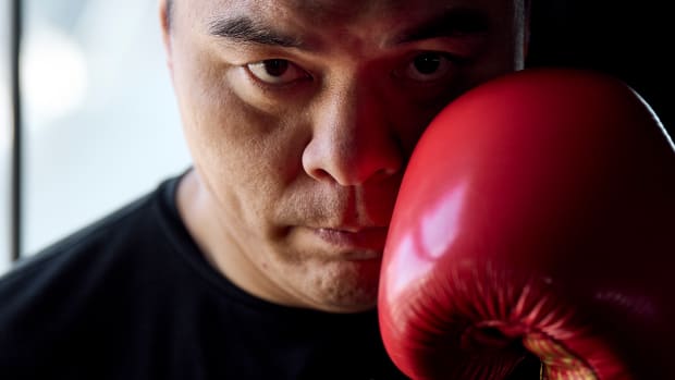 A close up of boxer Zhilei Zhang holding up a red glove near his face.