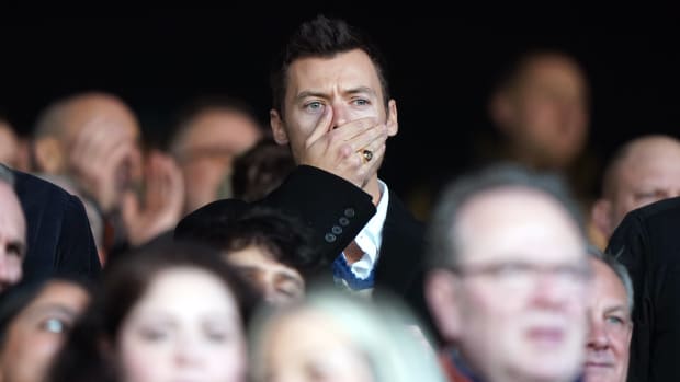 Harry Styles pictured covering his mouth with his hand while watching the Premier League game between Luton Town and Manchester United at Kenilworth Road in February 2024