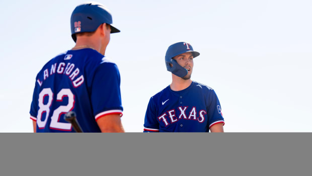 Texas Rangers rising star Evan Carter, right, left Sunday's spring training game after he was hit by a pitch on his left hand in the first inning.