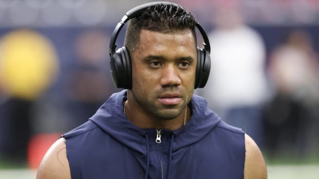Broncos quarterback Russell Wilson listens to headphones while warming up before a game.