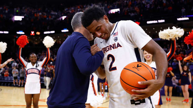 Tony Bennett embraces Reece Beekman after giving him a ball commemorating him becoming the all-time steals leader in the history of the Virginia men's basketball program.