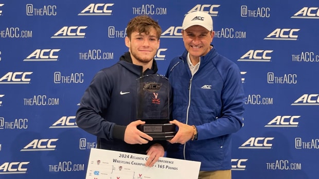 Virginia wrestler Nick Hamilton poses with ACC Commissioner Jim Phillips while holding the trophy for winning the ACC Wrestling Championship at 165 pounds.