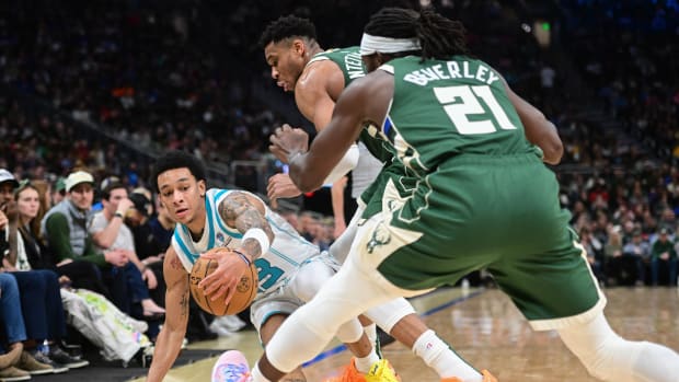 Charlotte Hornets guard Tre Mann (23) reaches for a loose ball against Milwaukee Bucks forward Giannis Antetokounmpo (34) and guard Patrick Beverley (21) 